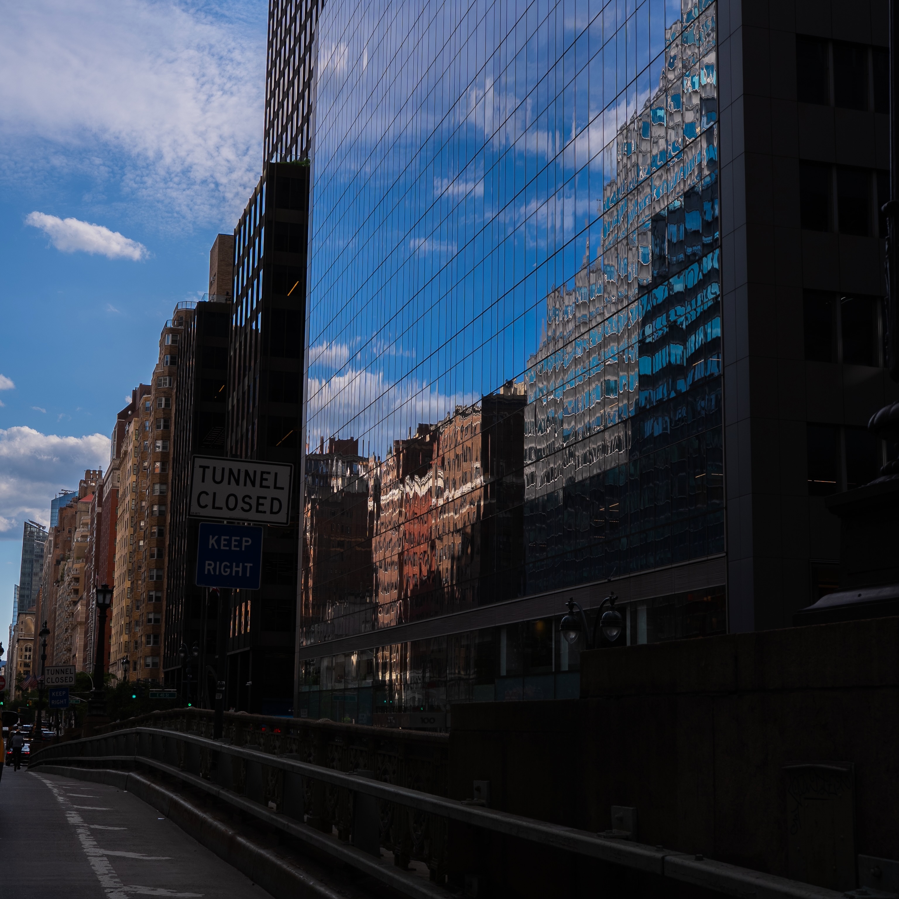 Blue sky and brick buildings reflected in a glass facade